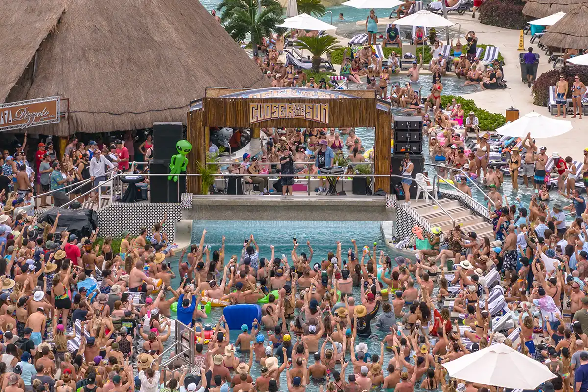Daytime poolside set with people floating in front of the stage with their hands up.