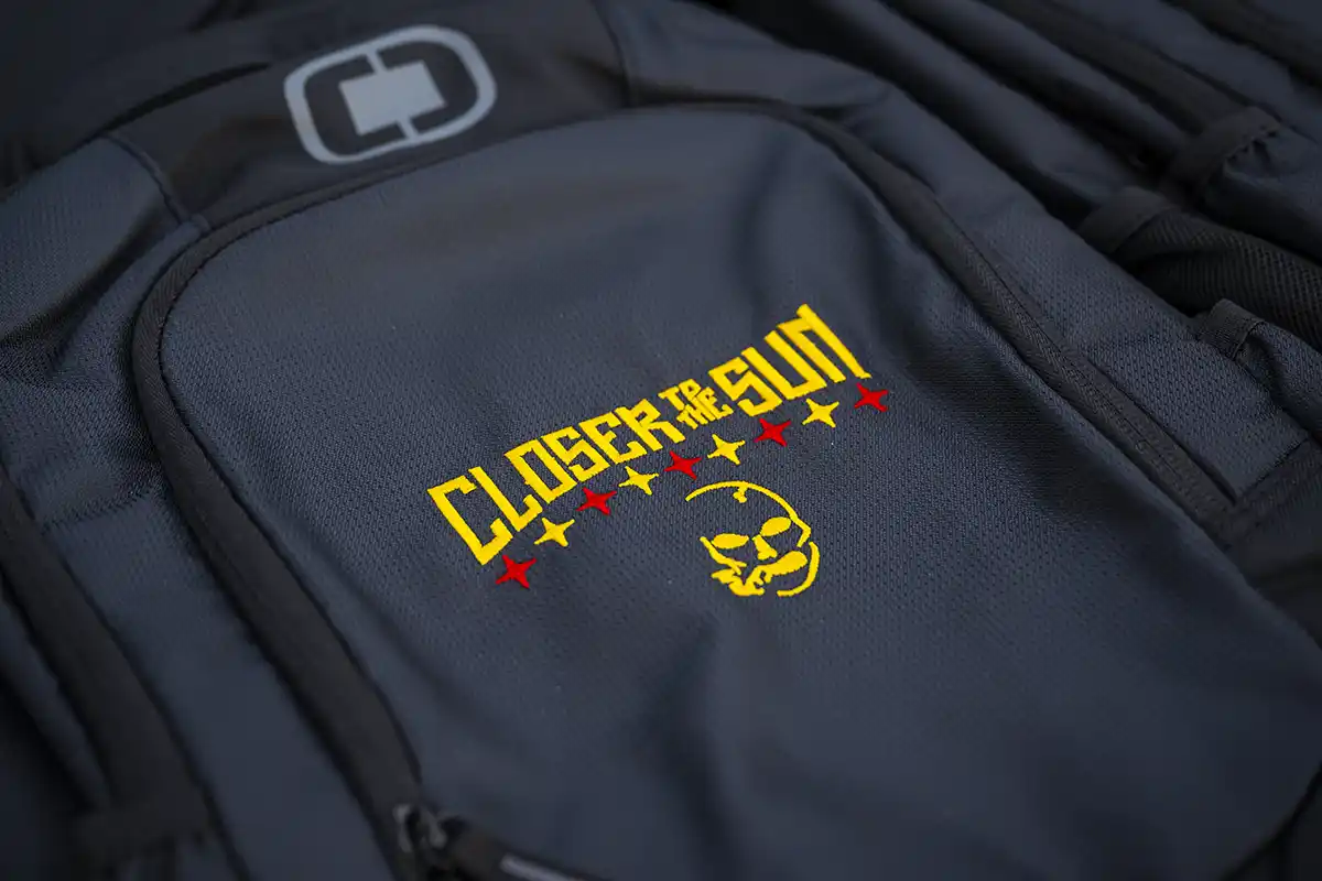 A close up photo of a Closer to the Sun branded backpack.