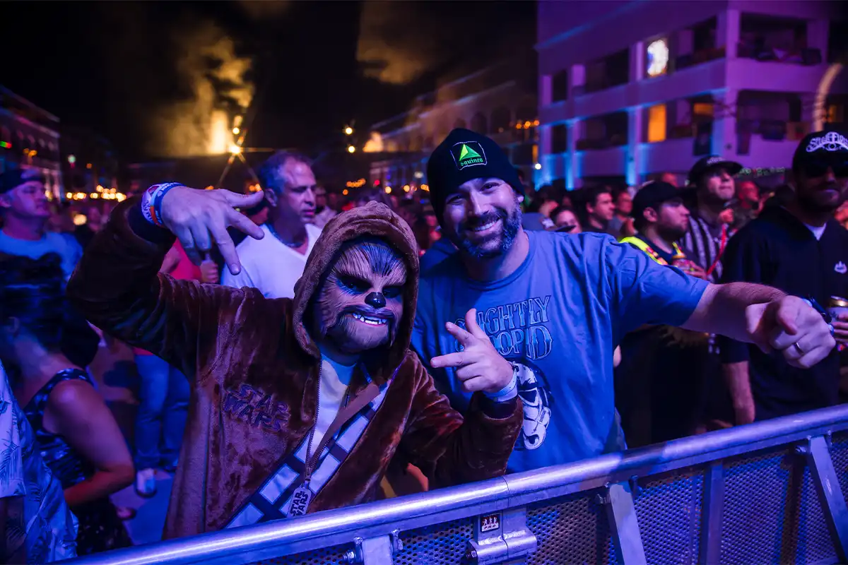 Guests posing in front of the Main Stage barrier railing in theme night costumes.