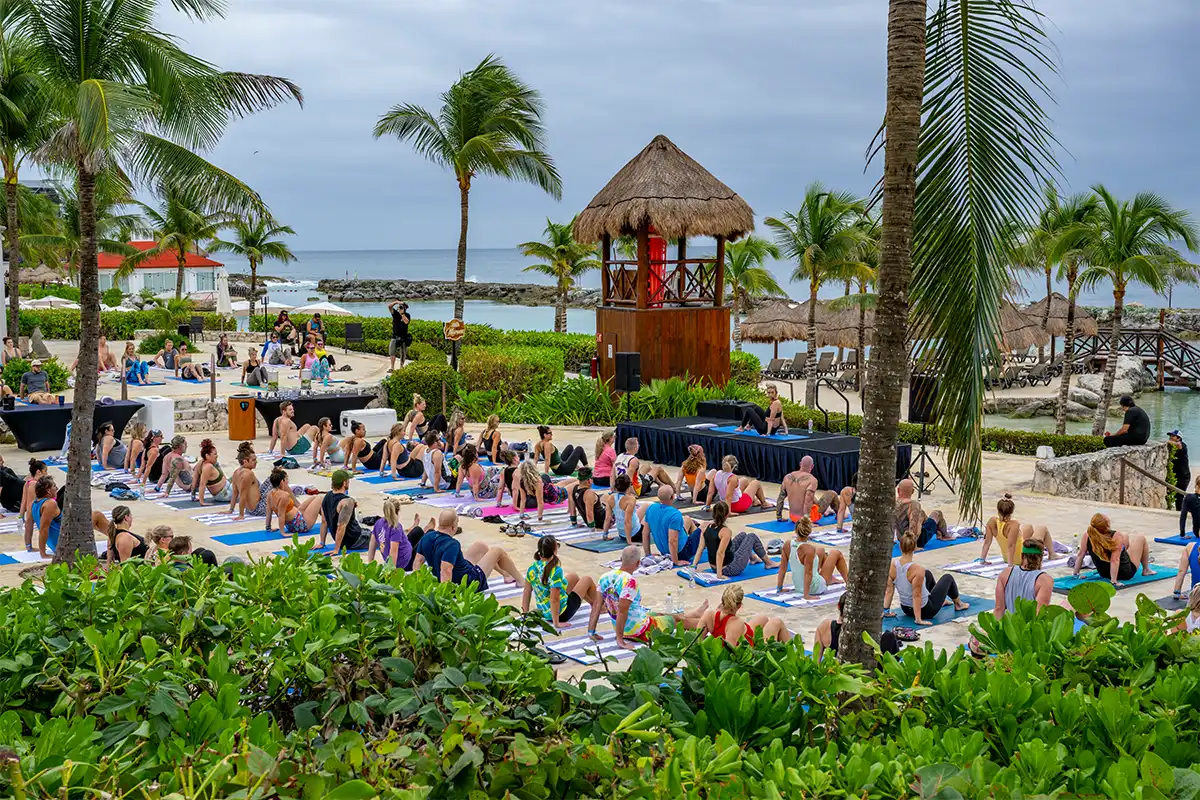Wide view of group morning yoga session with ocean view in background.