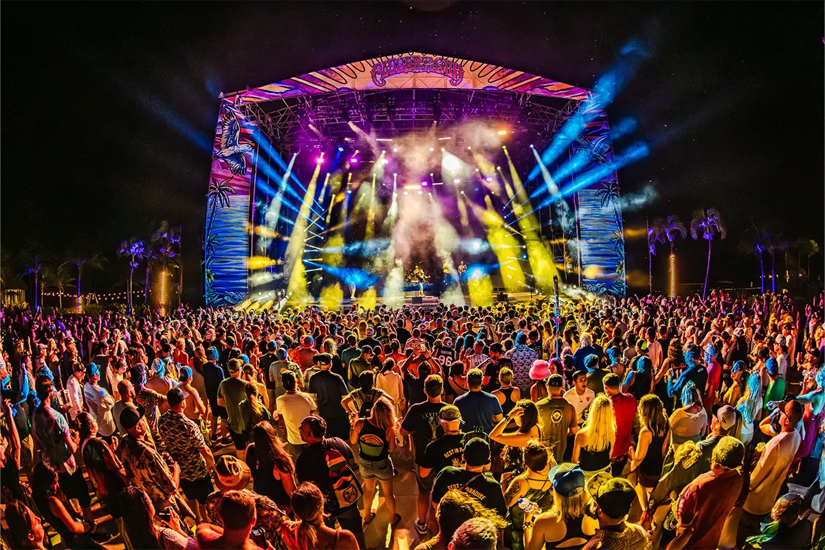 Wide angle view of the Main Stage with bright lights shining across the crowd of people.