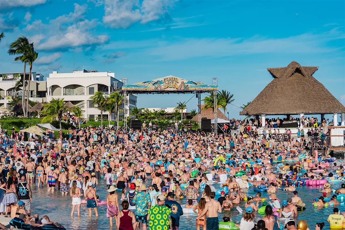 A wide view of the Beach Stage, with guests watching a daytime concert while in the lagoon.